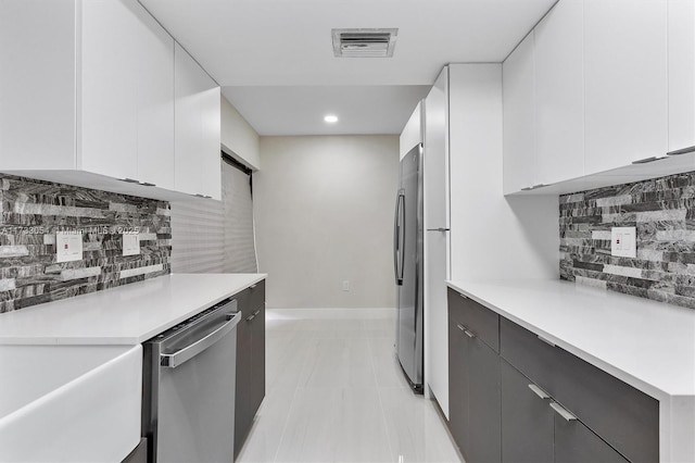 kitchen with tasteful backsplash, stainless steel appliances, light tile patterned floors, and white cabinets