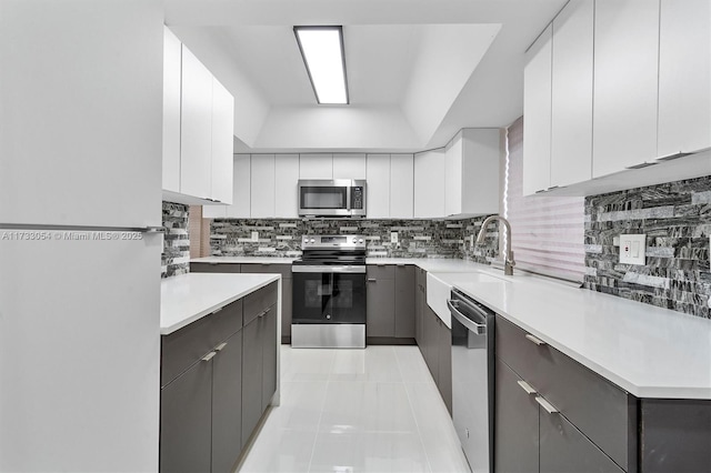 kitchen featuring light tile patterned flooring, tasteful backsplash, white cabinetry, sink, and stainless steel appliances