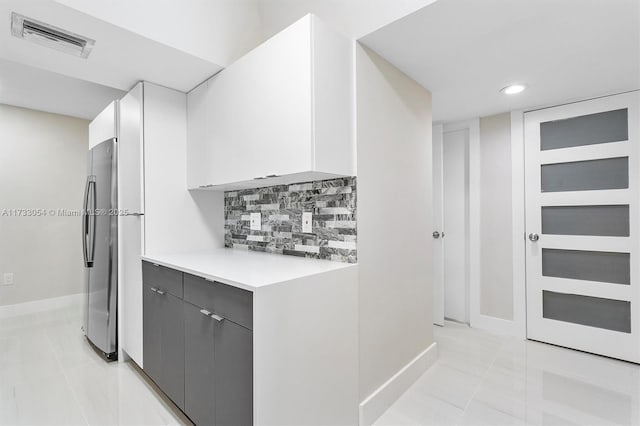 kitchen featuring white cabinetry, tasteful backsplash, light tile patterned floors, stainless steel fridge, and gray cabinets