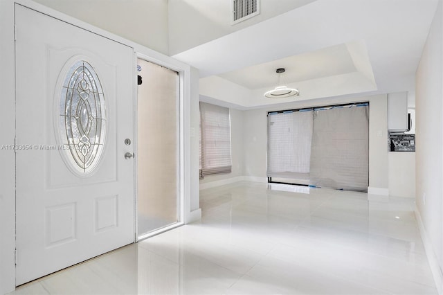 tiled foyer entrance with a tray ceiling