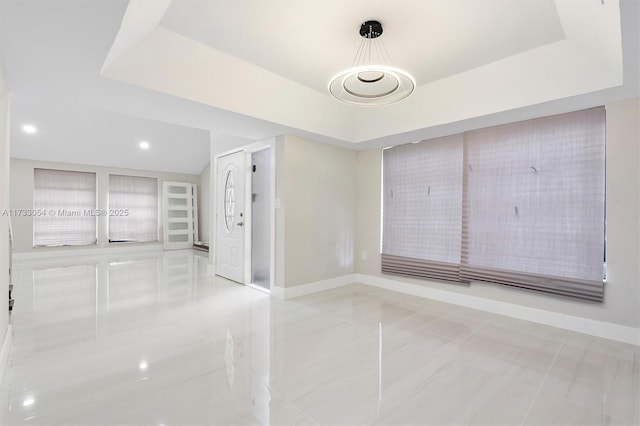 tiled empty room featuring a raised ceiling