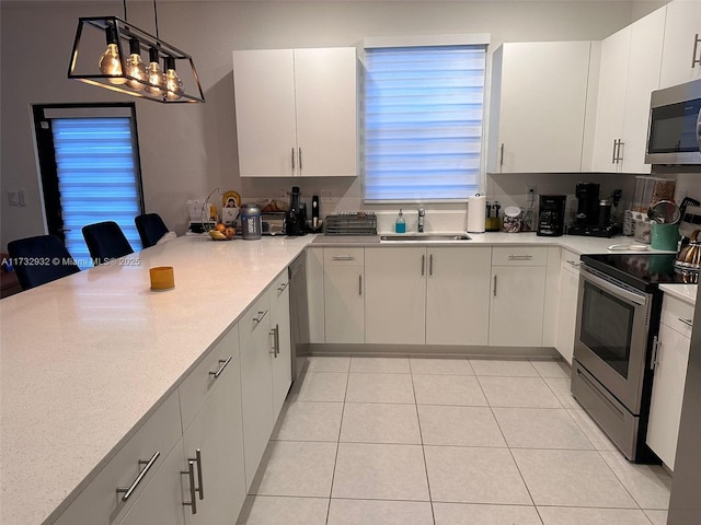 kitchen with white cabinetry, hanging light fixtures, stainless steel appliances, and sink