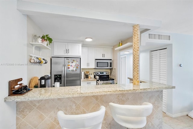 2160 SW 16th Ave Unit 212, Miami, FL 33145 - kitchen with visible vents, open shelves, light tile patterned flooring, white cabinets, and stainless steel appliances