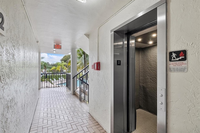 interior space featuring brick floor, elevator, and a textured wall