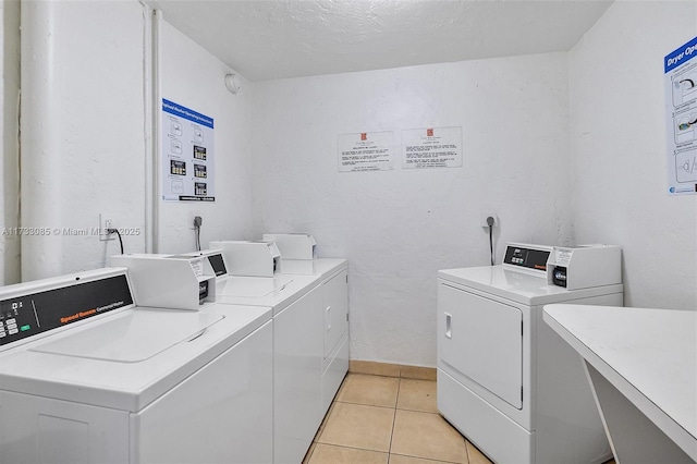 common laundry area with light tile patterned floors, a textured ceiling, baseboards, and separate washer and dryer