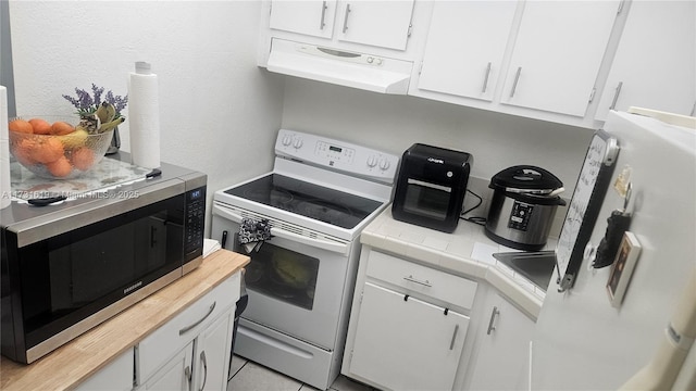 kitchen with white electric range oven, tile countertops, stainless steel microwave, under cabinet range hood, and white cabinetry