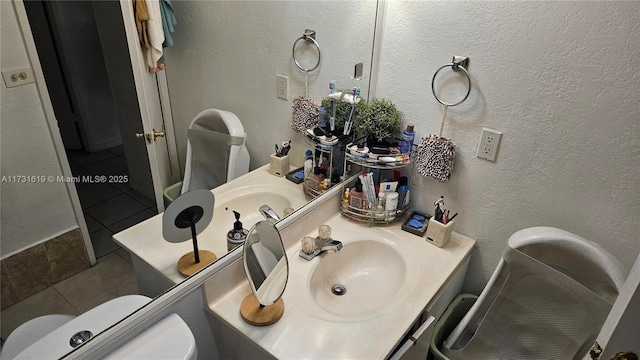 bathroom with a textured wall, vanity, toilet, and tile patterned floors