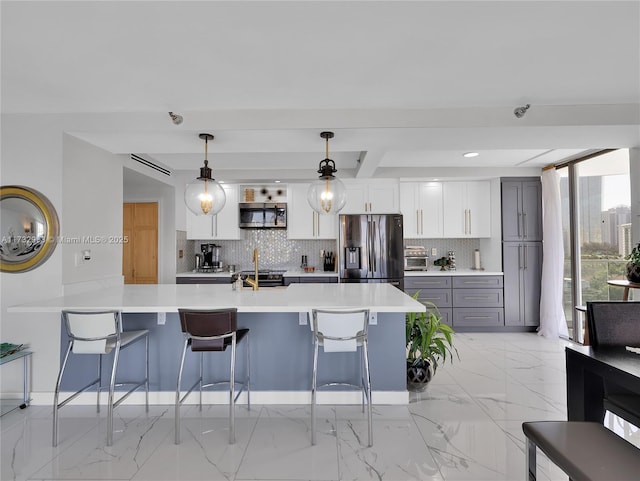 kitchen featuring appliances with stainless steel finishes, gray cabinetry, white cabinets, and a kitchen breakfast bar