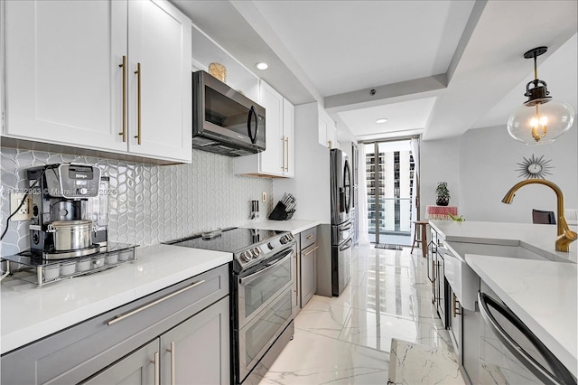 kitchen with tasteful backsplash, light stone counters, decorative light fixtures, stainless steel appliances, and white cabinets