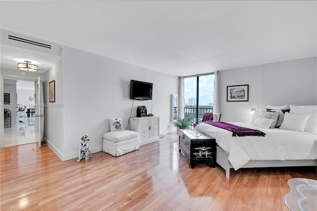 bedroom with expansive windows and light hardwood / wood-style floors