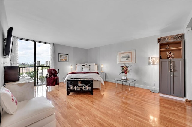 bedroom featuring expansive windows, light hardwood / wood-style flooring, and access to outside