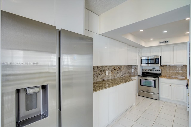 kitchen featuring light stone counters, appliances with stainless steel finishes, tasteful backsplash, and white cabinets