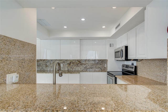 kitchen with white cabinetry, tasteful backsplash, light stone countertops, and appliances with stainless steel finishes