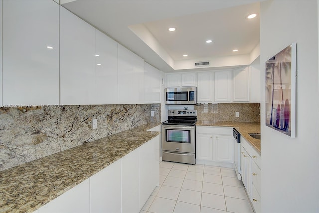 kitchen with white cabinetry, decorative backsplash, stainless steel appliances, and stone countertops