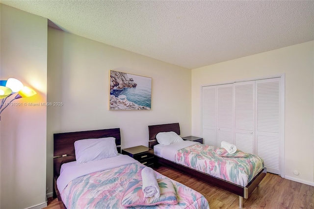 bedroom with wood-type flooring, a closet, and a textured ceiling