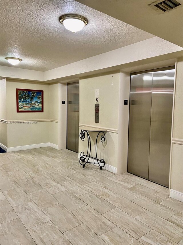 interior space with a textured ceiling and elevator