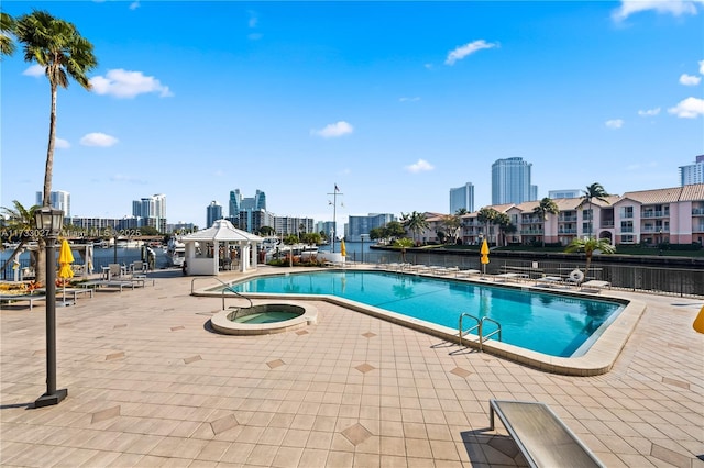 community pool featuring a view of city, a community hot tub, a patio area, and a water view