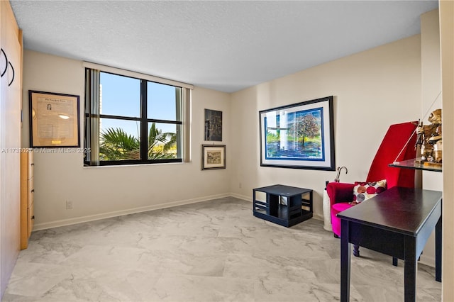 office space featuring a textured ceiling, marble finish floor, and baseboards