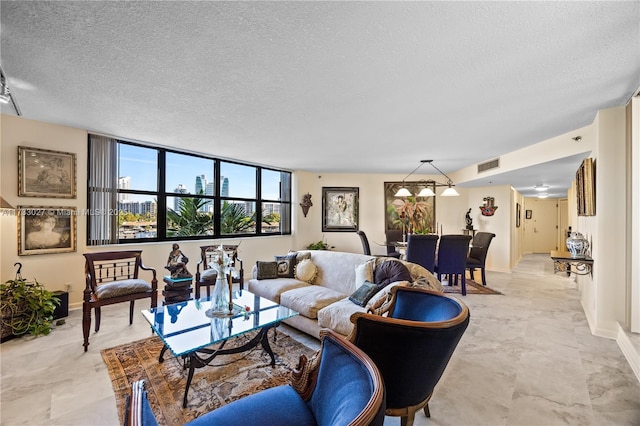 living area with marble finish floor, baseboards, visible vents, and a textured ceiling