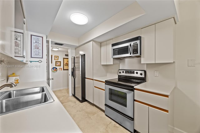 kitchen featuring visible vents, white cabinets, stainless steel appliances, light countertops, and a sink