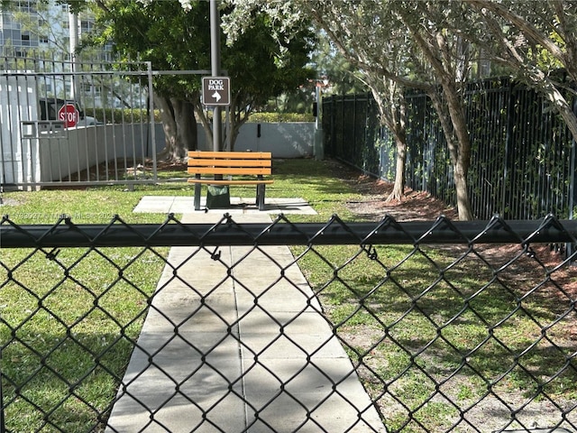 view of community with a gate, fence, and a yard