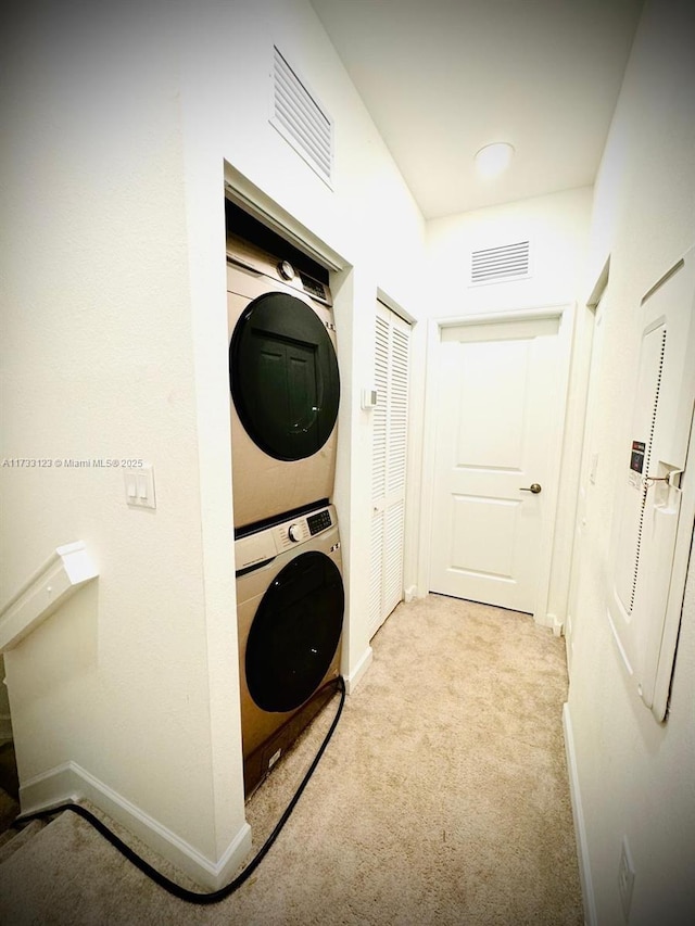 laundry area featuring stacked washing maching and dryer and light carpet