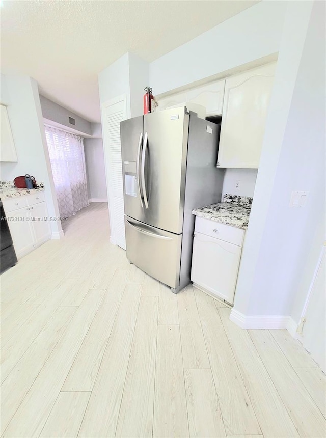 kitchen with light hardwood / wood-style flooring, white cabinets, and stainless steel refrigerator with ice dispenser