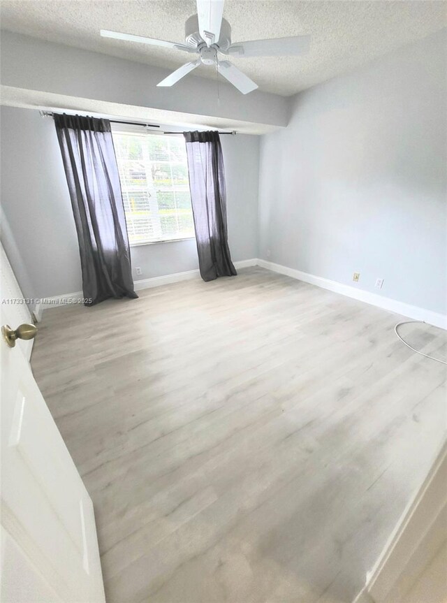 spare room with ceiling fan, light hardwood / wood-style floors, and a textured ceiling