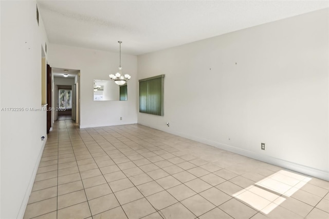 tiled spare room featuring lofted ceiling and a chandelier