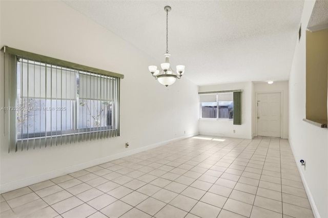 tiled empty room featuring lofted ceiling, a notable chandelier, and a textured ceiling