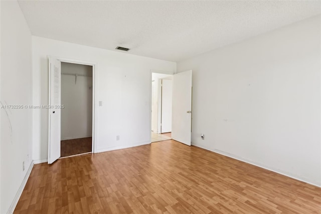 unfurnished bedroom with a closet, a textured ceiling, and light wood-type flooring