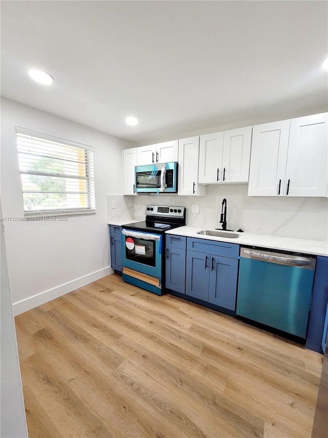 kitchen featuring blue cabinets, sink, white cabinetry, appliances with stainless steel finishes, and light hardwood / wood-style floors