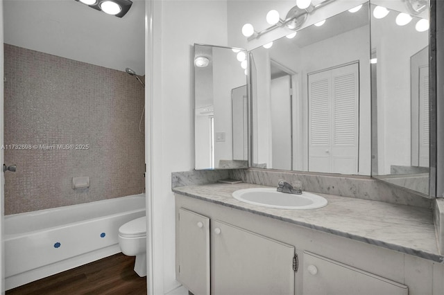 full bathroom featuring vanity, tiled shower / bath combo, wood-type flooring, and toilet