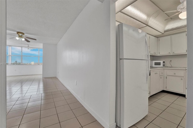 kitchen featuring ceiling fan, white appliances, light tile patterned floors, and white cabinets