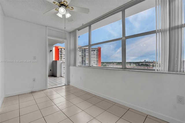 empty room featuring ceiling fan, a textured ceiling, and light tile patterned floors