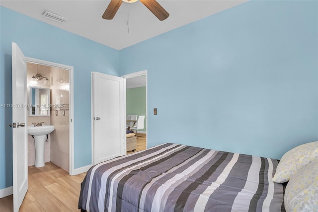 bedroom featuring sink, light hardwood / wood-style flooring, ceiling fan, and ensuite bath