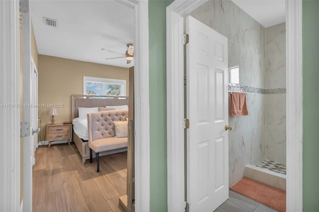 bathroom featuring hardwood / wood-style flooring and a tile shower