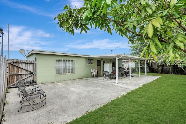 back of property with a patio area and a lawn