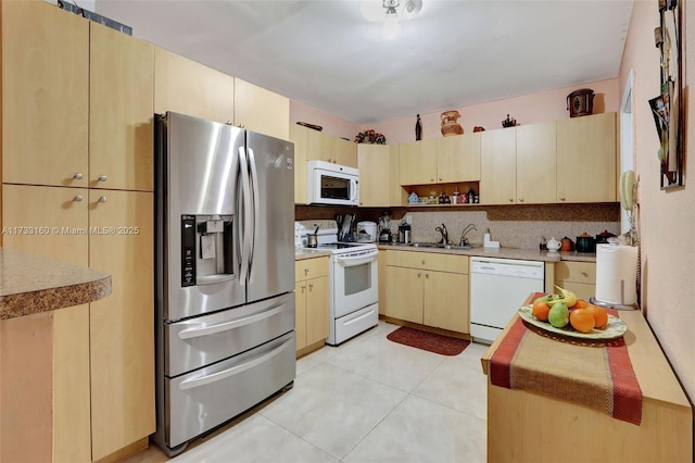 kitchen featuring light tile patterned flooring, light brown cabinetry, sink, white appliances, and backsplash