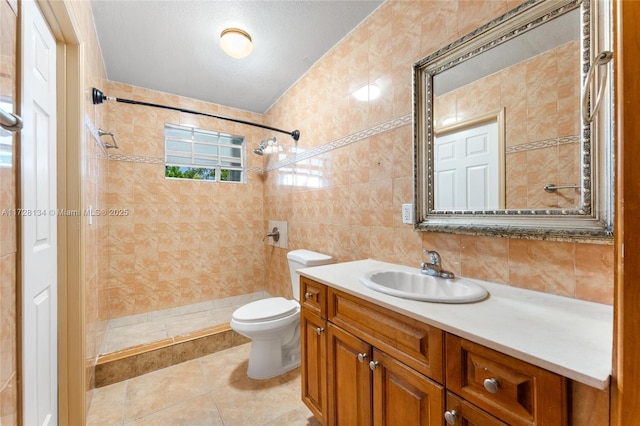 bathroom with tile patterned floors, toilet, tile walls, a tile shower, and vanity