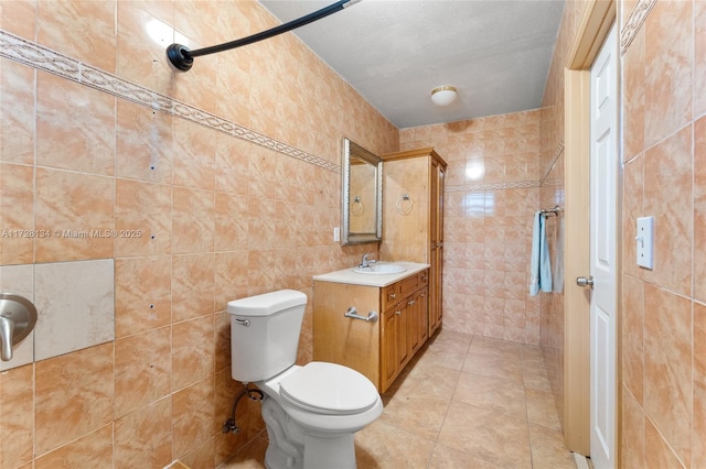 bathroom with vanity, toilet, tile walls, and a textured ceiling