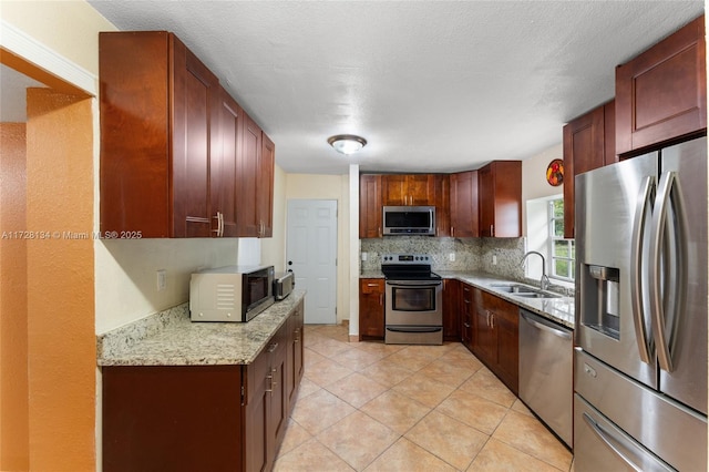 kitchen with light tile patterned flooring, sink, tasteful backsplash, appliances with stainless steel finishes, and light stone countertops