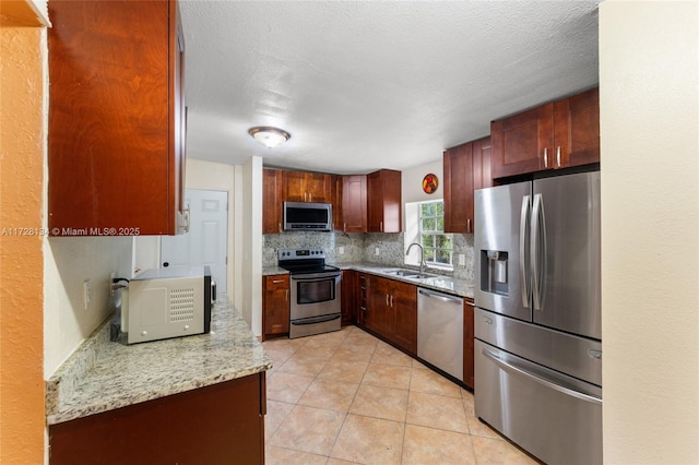 kitchen featuring light tile patterned flooring, sink, tasteful backsplash, appliances with stainless steel finishes, and light stone countertops