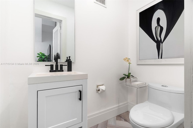 bathroom with parquet flooring, vanity, and toilet