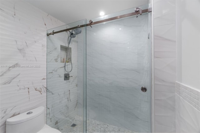 bathroom with a shower with door, tile walls, and toilet