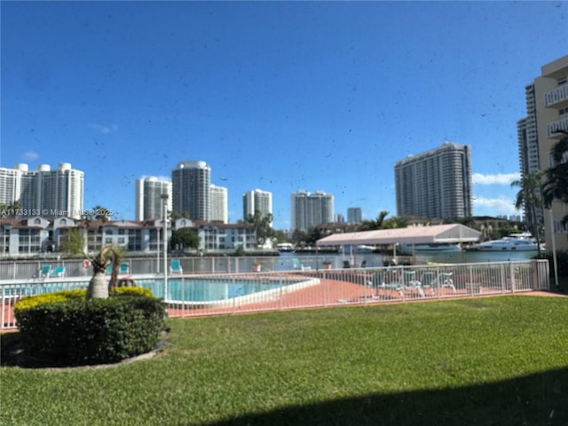 view of pool with a water view and a yard