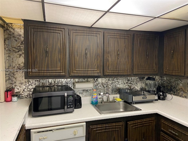 kitchen with white dishwasher, sink, and dark brown cabinetry