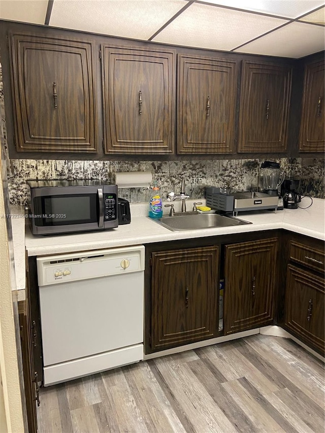 kitchen with dark brown cabinetry, dishwasher, sink, and light hardwood / wood-style flooring