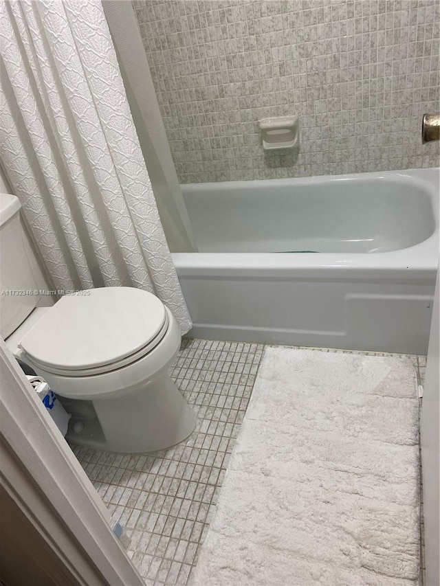 bathroom featuring shower / tub combo with curtain, tile patterned floors, and toilet