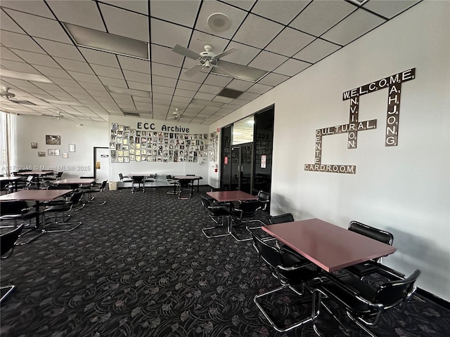 dining space with ceiling fan, carpet flooring, and a drop ceiling